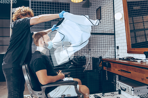 Image of Man getting hair cut at the barbershop wearing mask during coron