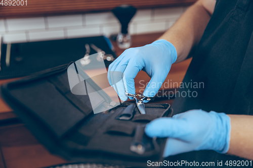 Image of Male barber at the barbershop wearing gloves preparing working place for client