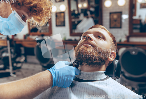 Image of Man getting hair cut at the barbershop wearing mask during coronavirus pandemic