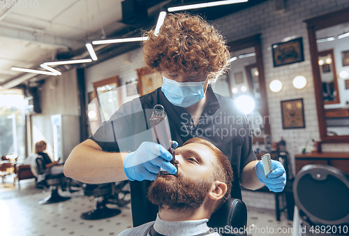 Image of Man getting hair cut at the barbershop wearing mask during coronavirus pandemic