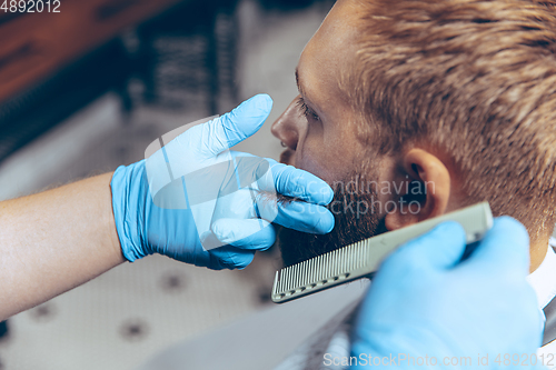 Image of Man getting hair cut at the barbershop wearing mask during coronavirus pandemic