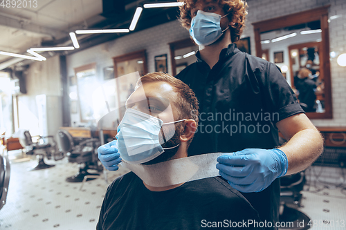 Image of Man getting hair cut at the barbershop wearing mask during coron
