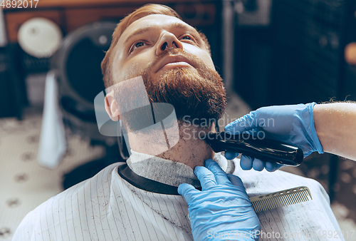 Image of Man getting hair cut at the barbershop wearing mask during coronavirus pandemic