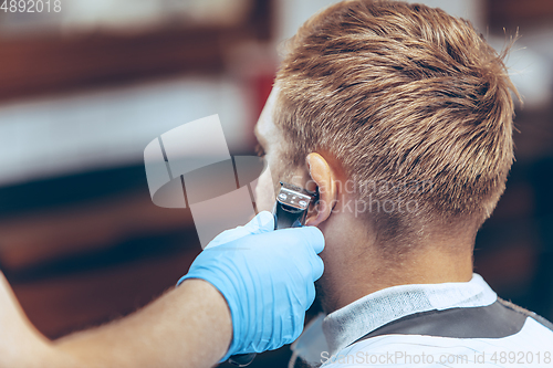 Image of Man getting hair cut at the barbershop wearing mask during coronavirus pandemic