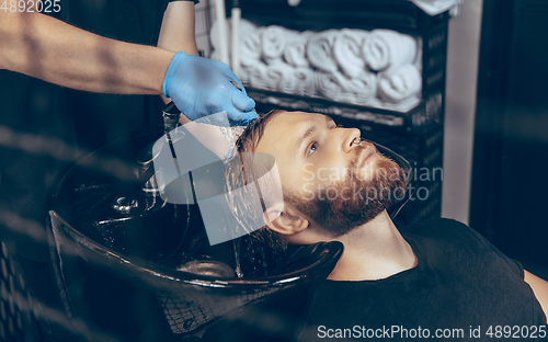 Image of Man getting hair cut at the barbershop wearing mask during coronavirus pandemic