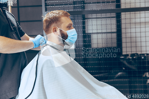 Image of Man getting hair cut at the barbershop wearing mask during coron