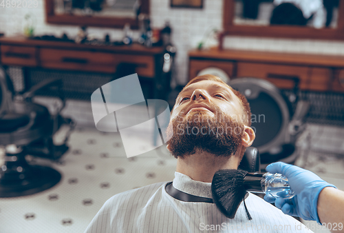 Image of Man getting hair cut at the barbershop wearing mask during coronavirus pandemic