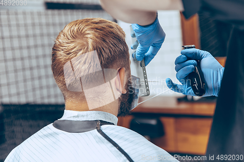 Image of Man getting hair cut at the barbershop wearing mask during coronavirus pandemic