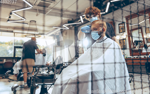 Image of Man getting hair cut at the barbershop wearing mask during coronavirus pandemic