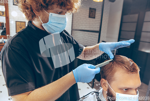 Image of Man getting hair cut at the barbershop wearing mask during coronavirus pandemic