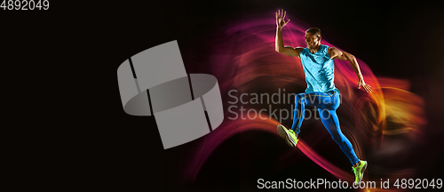 Image of Professional male runner training isolated on black studio background in mixed light