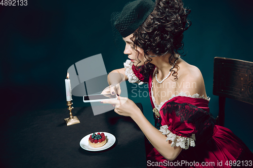 Image of Young woman as Anna Karenina on dark blue background. Retro style, comparison of eras concept.