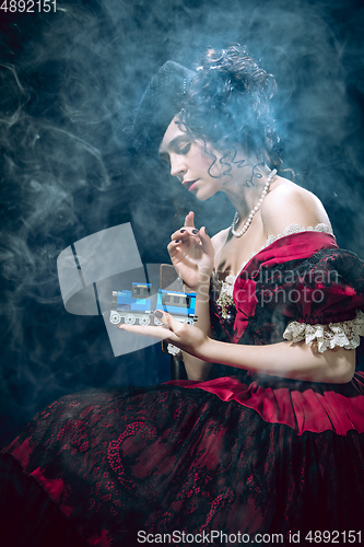 Image of Young woman as Anna Karenina on dark blue background. Retro style, comparison of eras concept.