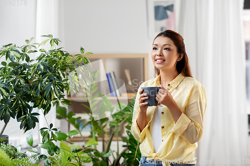 Image of happy smiling asian woman drinking coffee at home