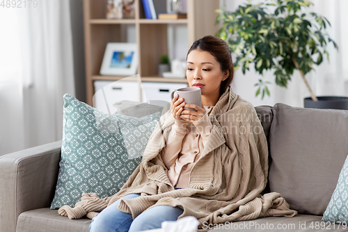 Image of sad sick asian woman drinking hot tea at home