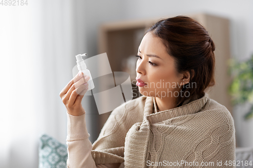 Image of sick asian woman with oral spray medicine at home