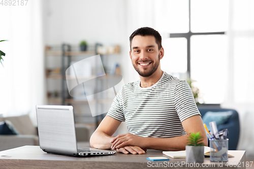 Image of happy man with laptop working at home office