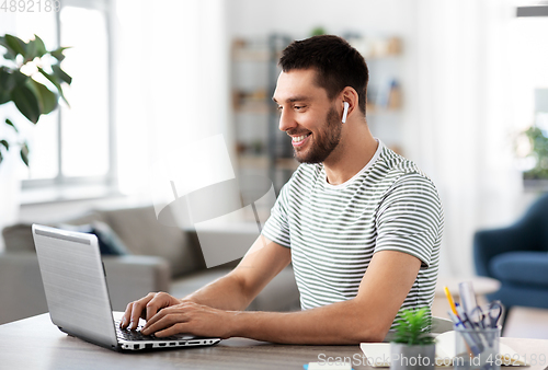 Image of man with laptop and earphones at home office