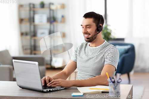 Image of man with headset and laptop working at home