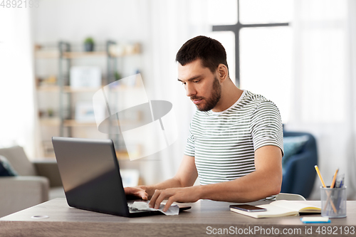 Image of man cleaning laptop with wet wipe at home office