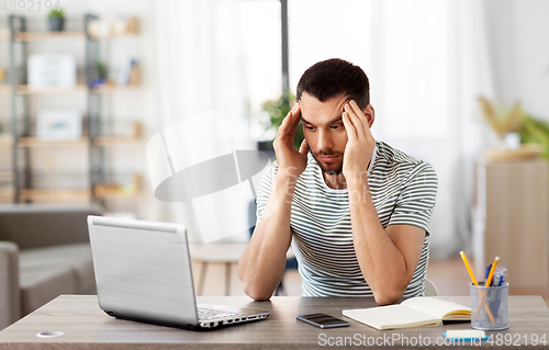 Image of stressed man with laptop working at home office