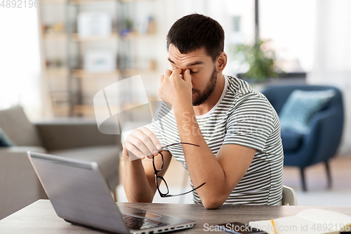 Image of tired man with laptop working at home office