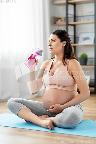 Image of pregnant woman drinking water after yoga at home