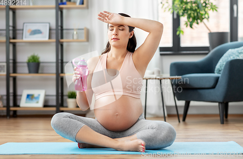 Image of pregnant woman drinking water after yoga at home