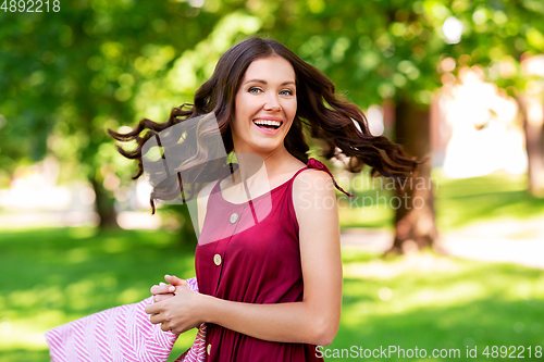 Image of happy woman with picnic blanket at park