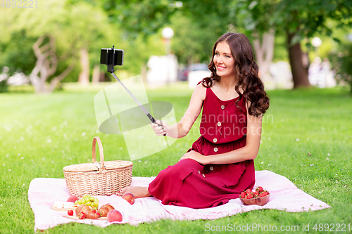 Image of happy woman with smartphone taking selfie at park