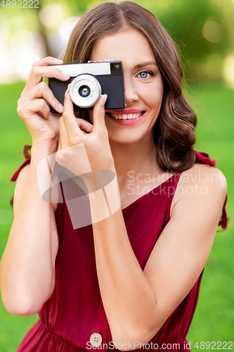 Image of happy woman with camera photographing at park