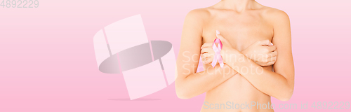 Image of young woman checking breast for signs of cancer