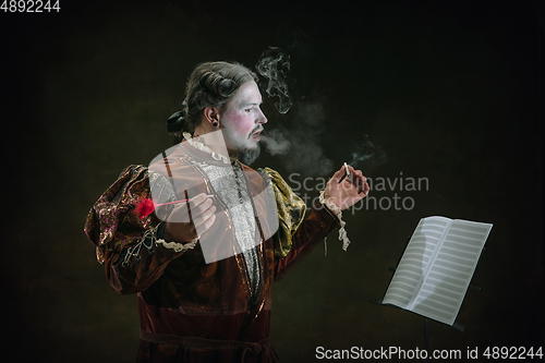 Image of Young man as Johann Sebastian Bach on dark green background. Retro style, comparison of eras concept.