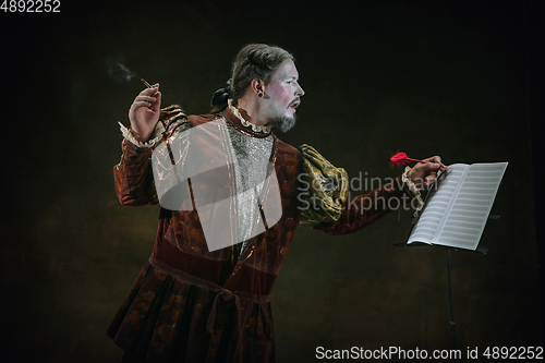Image of Young man as Johann Sebastian Bach on dark green background. Retro style, comparison of eras concept.