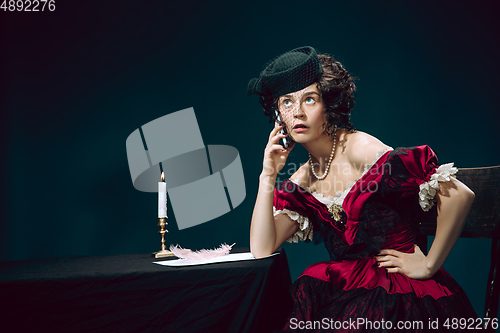 Image of Young woman as Anna Karenina on dark blue background. Retro style, comparison of eras concept.