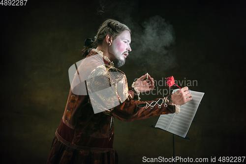 Image of Young man as Johann Sebastian Bach on dark green background. Retro style, comparison of eras concept.