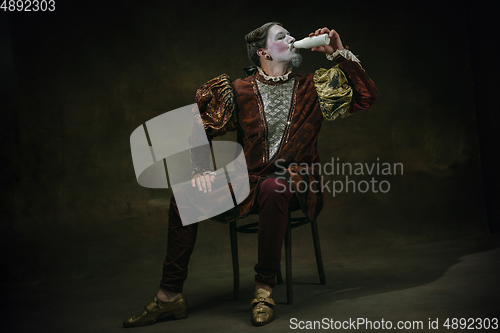 Image of Young man as Johann Sebastian Bach on dark green background. Retro style, comparison of eras concept.