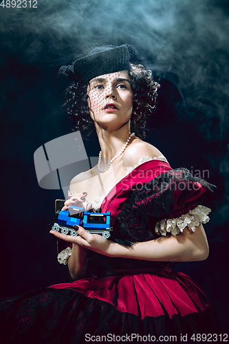 Image of Young woman as Anna Karenina on dark blue background. Retro style, comparison of eras concept.