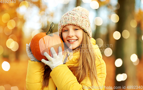 Image of happy girl with pumpkin at autumn park