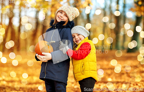 Image of happy children with pumpkin hugging at autumn park