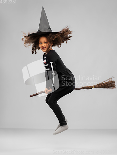 Image of girl in black witch hat with broom on halloween