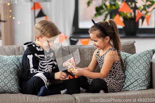 Image of kids in halloween costumes with candies at home