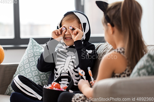 Image of kids in halloween costumes with candies at home
