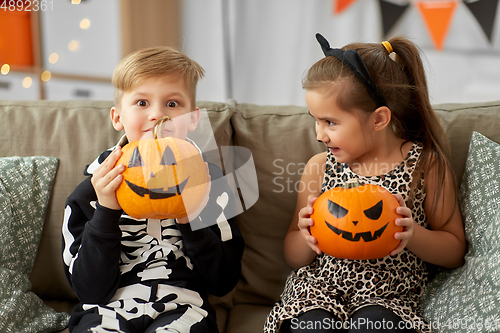 Image of kids in halloween costumes with pumpkins at home