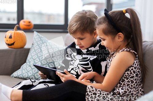 Image of kids in halloween costumes with tablet pc at home