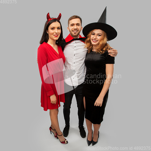 Image of happy friends in halloween costumes over grey