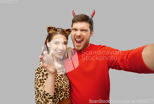 Image of happy couple in halloween costumes taking selfie