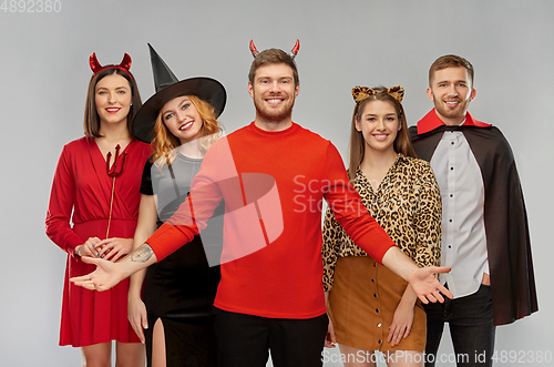 Image of happy friends in halloween costumes over grey