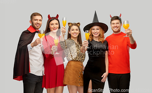 Image of happy friends in halloween costumes over grey