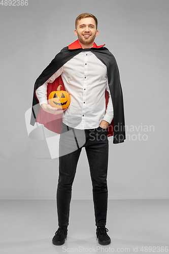 Image of man in halloween costume of vampire with pumpkin